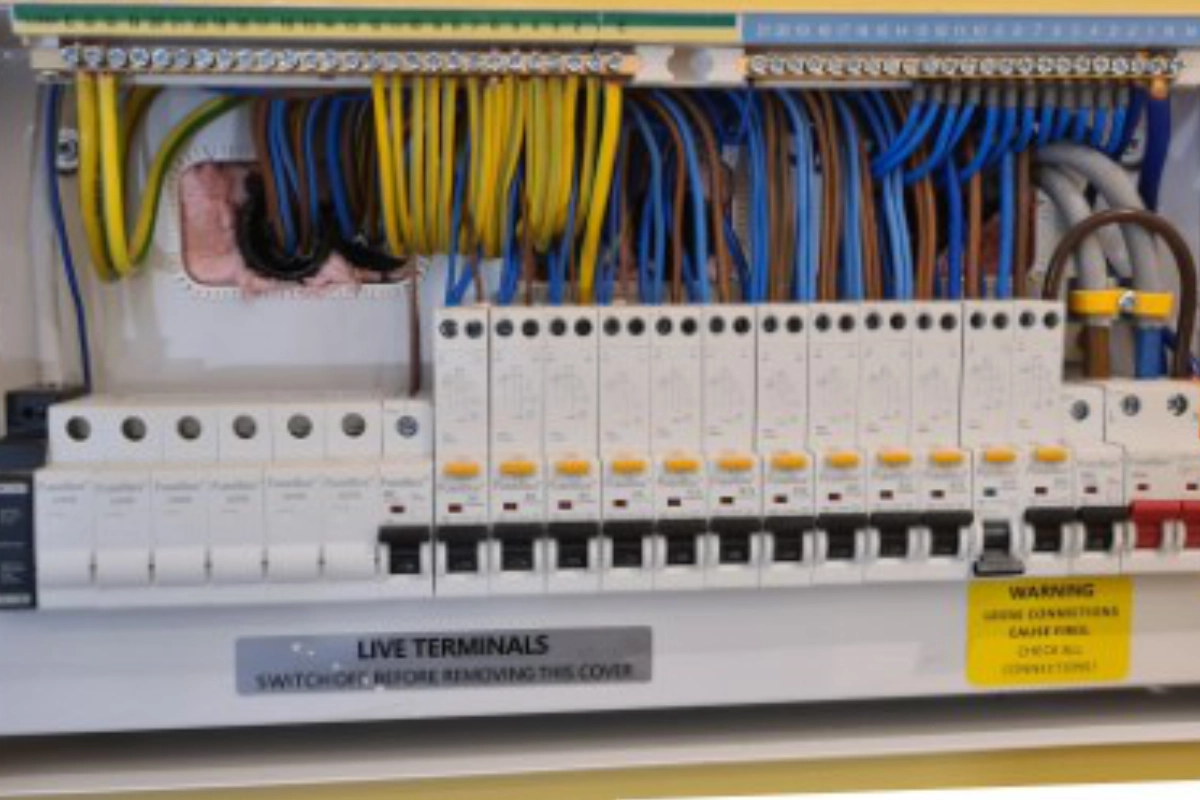 Open electrical consumer unit showing circuit breakers and neatly arranged wiring.