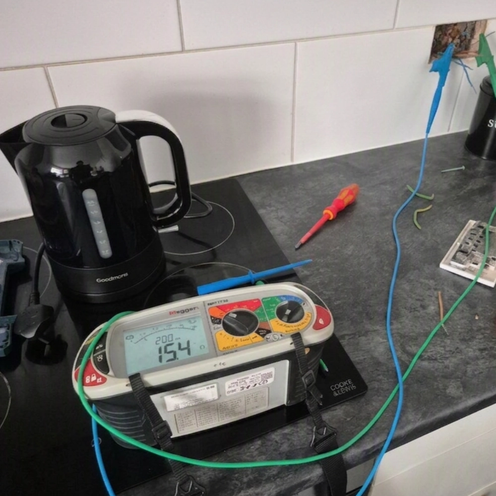 Electrical testing equipment connected to exposed wiring on a kitchen worktop.