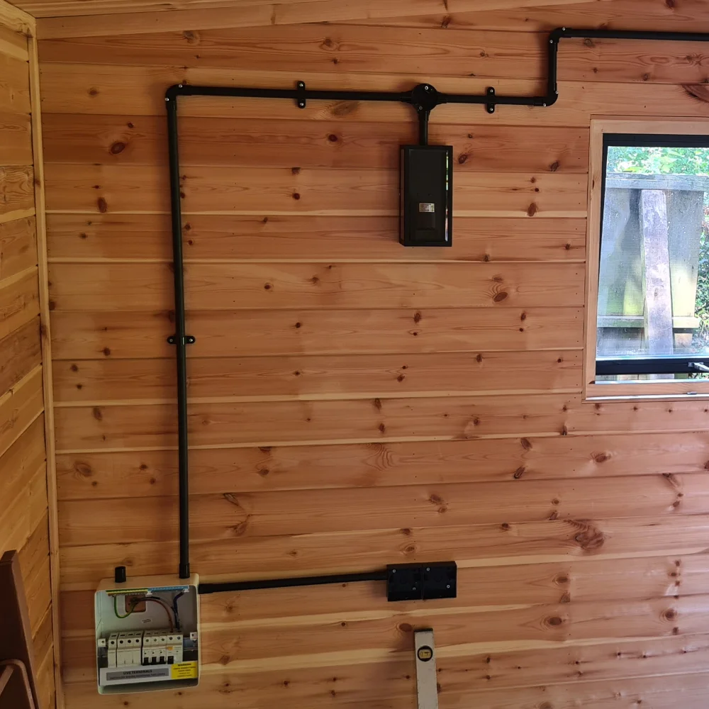 Surface-mounted electrical wiring, consumer unit and switches installed on a timber wall.